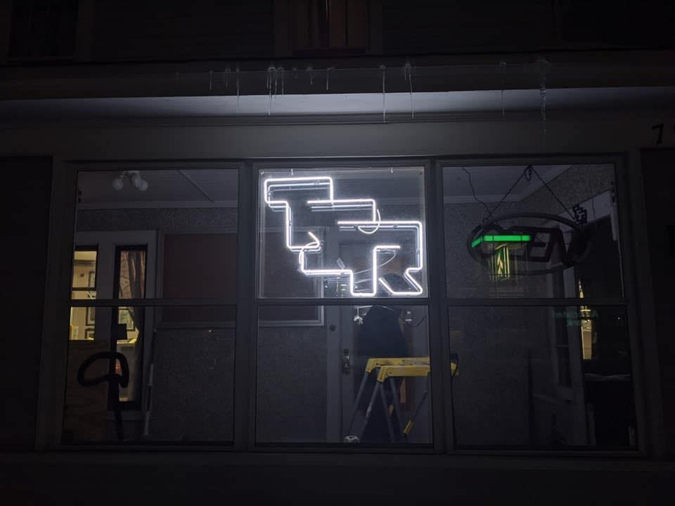 Photo of the Dungeon Hobby Shop Museum at night with all the lights out except for the TSR neon in the window.