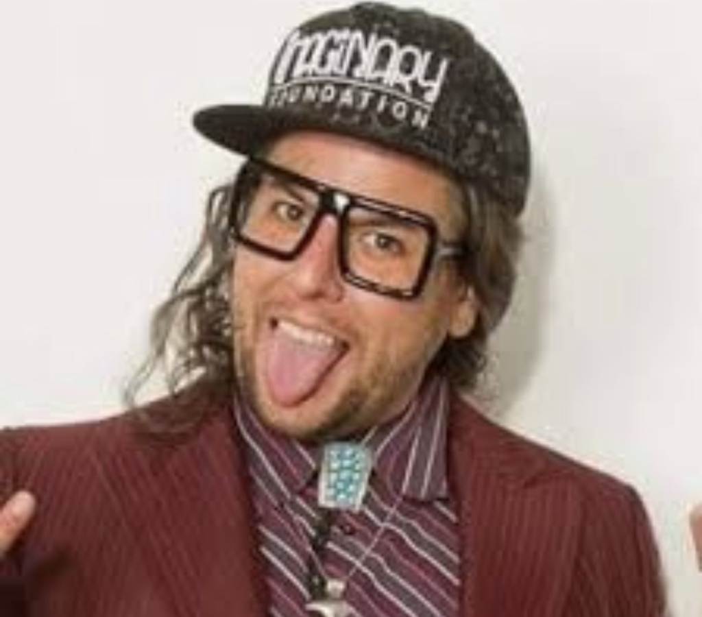 One of Stephen Dinehart's publicity photos with him in a garish maroon suit, a cap and lenseless thick frame glasses poking his tongue out like he's a rock star.