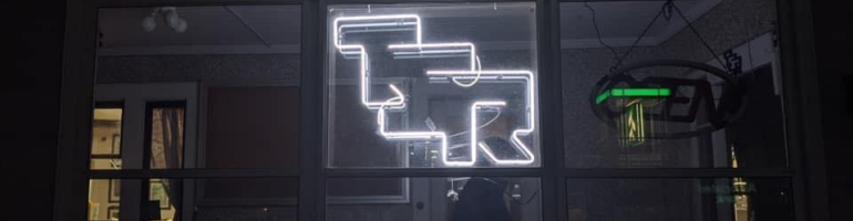 A photo from the TSR Dungeon Hobby Shop Museum, showing a LED (Neon) TSR sign in their window at night.