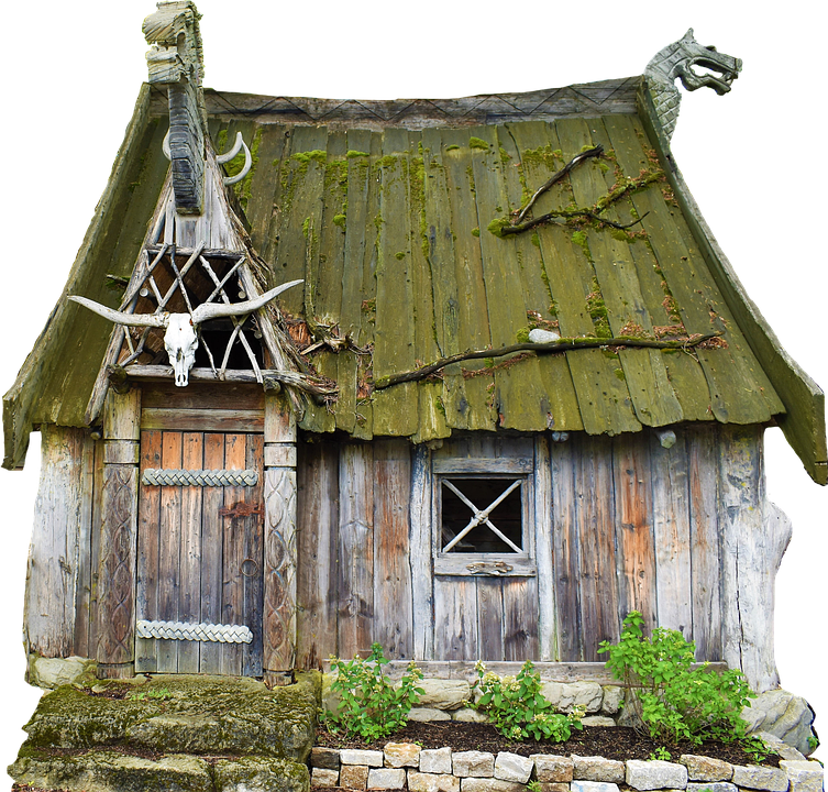 An olde cabin with a mouldy roof, a bull skull with horns hanging above the doorway, the timber looking weathered but the garden looking fresh and tended to.
